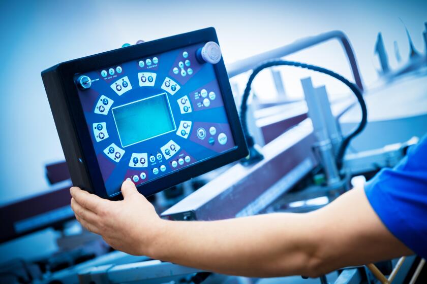 Worker programming print screening machine on the monitor. Industrial printer. Manufacture work.