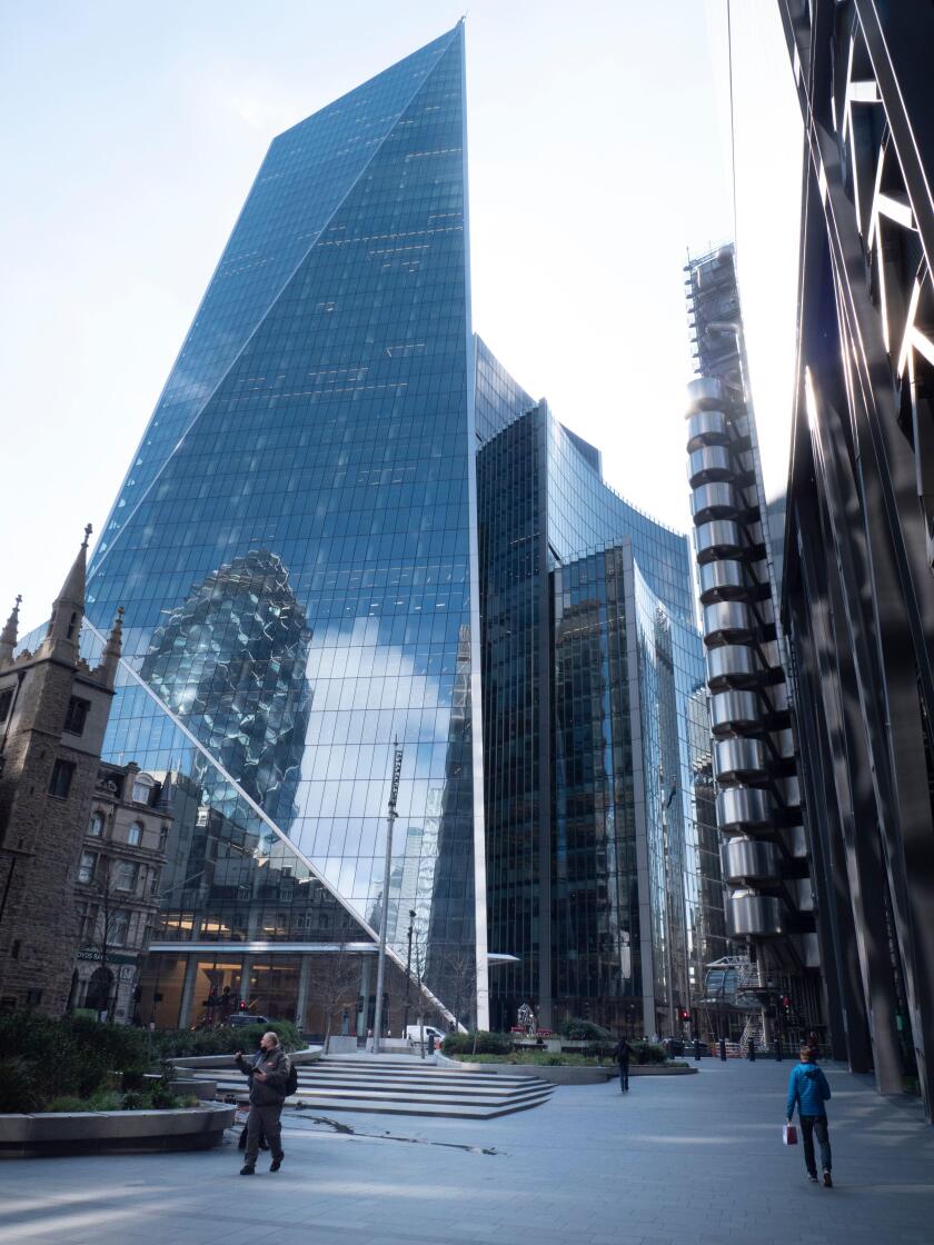 from left to right St Andrew Undershaft church, The Scalpel  skyscraper with Swiss Re reflected in windows,  Willis building, Lloyds insurance building, The Leadenhall building, with  pedestrian walking in quiet empty streets during coronavirus, Covid-19 