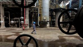 A worker walks past oil pipes at a refinery in Wuhan, Hubei province March 23, 2012. REUTERS/Stringer/File Photo