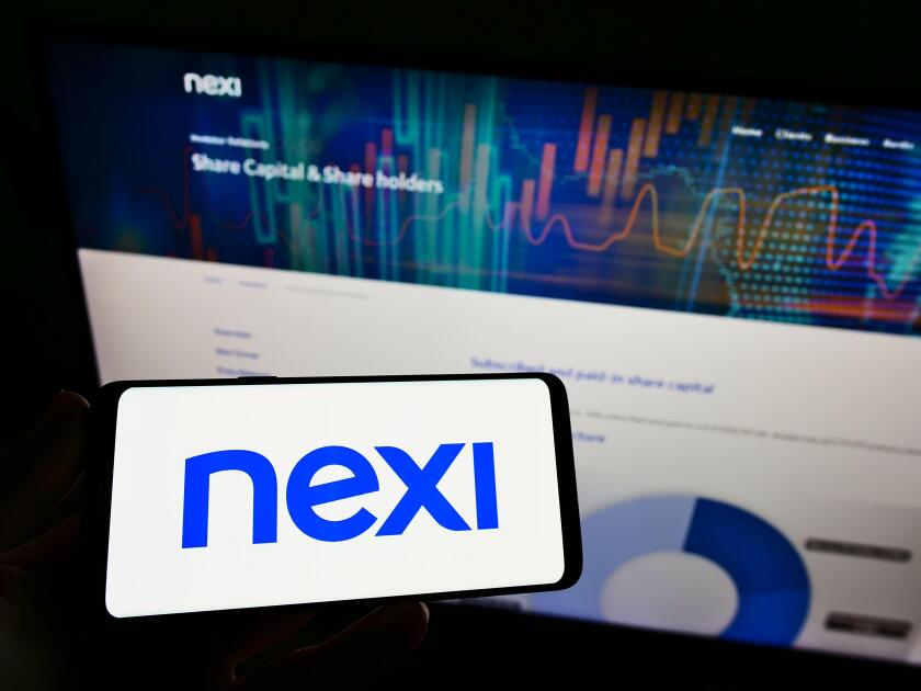 Person holding smartphone with logo of Italian bank Nexi S.p.A. on screen in front of website. Focus on phone display.