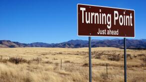 Turning Point Just Ahead  brown road sign with blue sky and wilderness