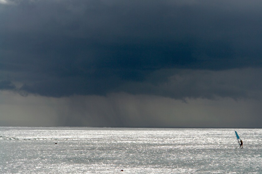 One surfer out at sea with a storm approaching, near Pointe aux Piments, Mauritius, Africa, Indian Ocean