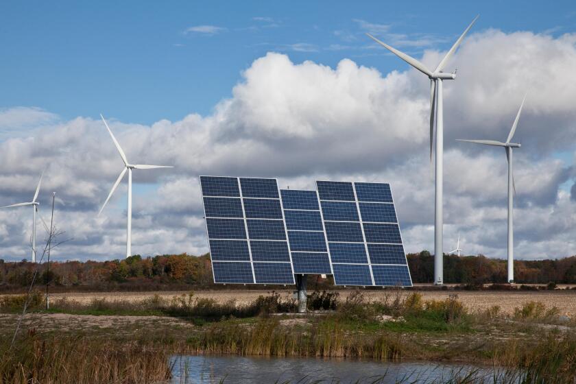 Solar panels on tracking system and windmills in farmland of southwestern Ontario (near Lake Erie), Ontario, Canada.