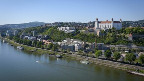 Bratislava Castle and the Old Town skyline over the Danube River, with bridge traffic and city landmarks on a clear day