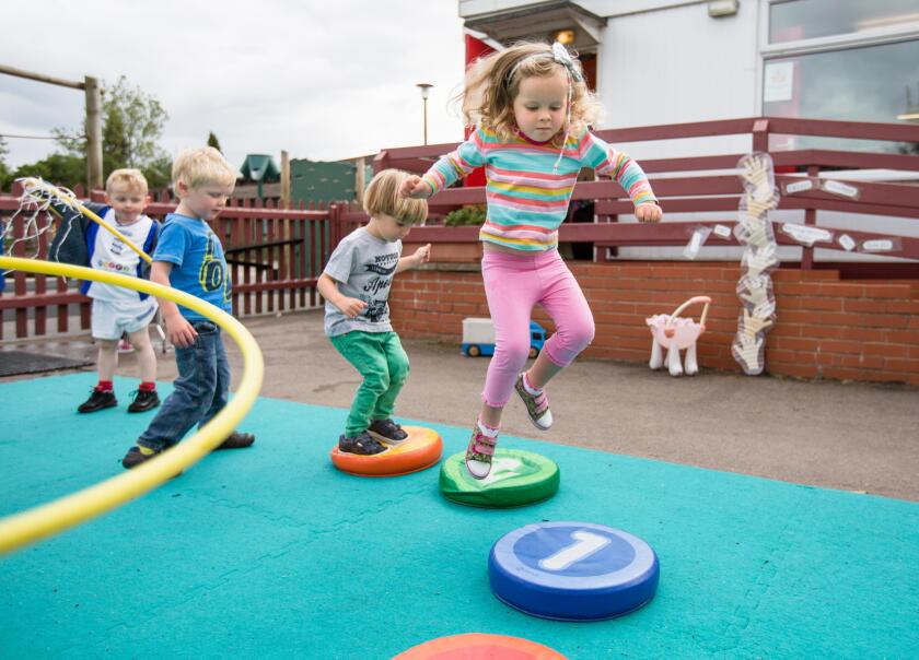 Nursery school children playing in a playground in Warwickshire, UK