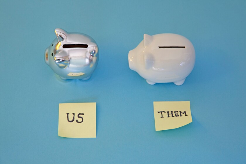 two piggy banks with post it notes of "us" and "them" .