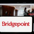 Person holding cellphone with logo of British investment company Bridgepoint Group plc in front of business webpage. Focus on phone display.