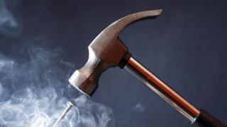 Work tool. Metal hammer above nail with smoke on nice dark background