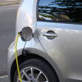 Silver electric car charging with a yellow cable plugged into its port.