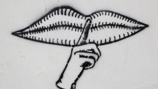 Graffito with closed mouth and a finger calling for silence