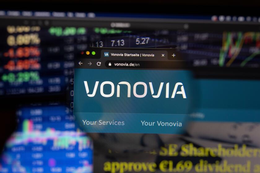 Vonovia company logo on a website with blurry stock market developments in the background, seen on a computer screen through a magnifying glass