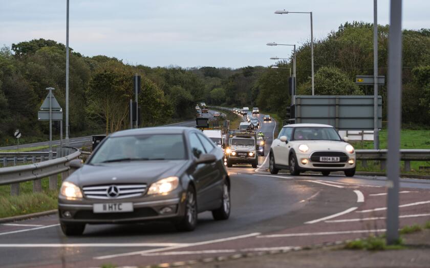 Cars with lights on in traffic being driven to work in the early morning rush hour, on the A27 road in the UK.