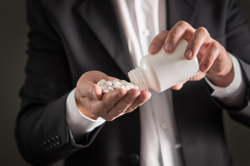 Pharmaceutical representative, consultant or head director or manager of medicine company with white tablets. Man in a suit pouring spilling pills.