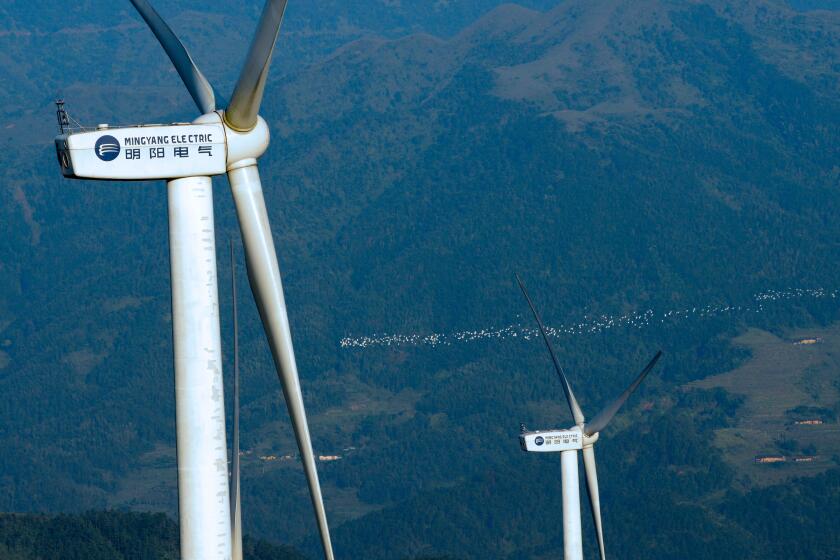 --FILE--Wind turbines manufactured by Mingyang Electric whirl to generate electricity at a wind farm on the outskirts of Xinyi city, south China's Gua