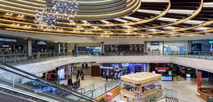 Modern multi-level retail atrium at Manchester Arndale Shopping Centre in Manchester, UK with glass balustrades and circular ceiling feature.