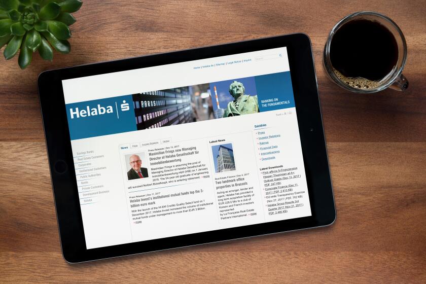 The website of Helaba is seen on an iPad tablet, on a wooden table along with an espresso coffee and a house plant (Editorial use only).