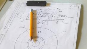 Drawing and pencil lies on a metal table at the factory
