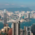 The skyline of Victoria Bay features impressive skyscrapers and busy harbor activities with a clear blue sky above.