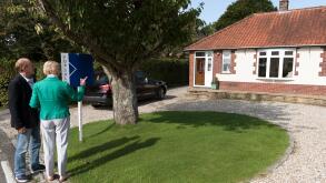 House buyers viewing a house with a for sale sign. England UK