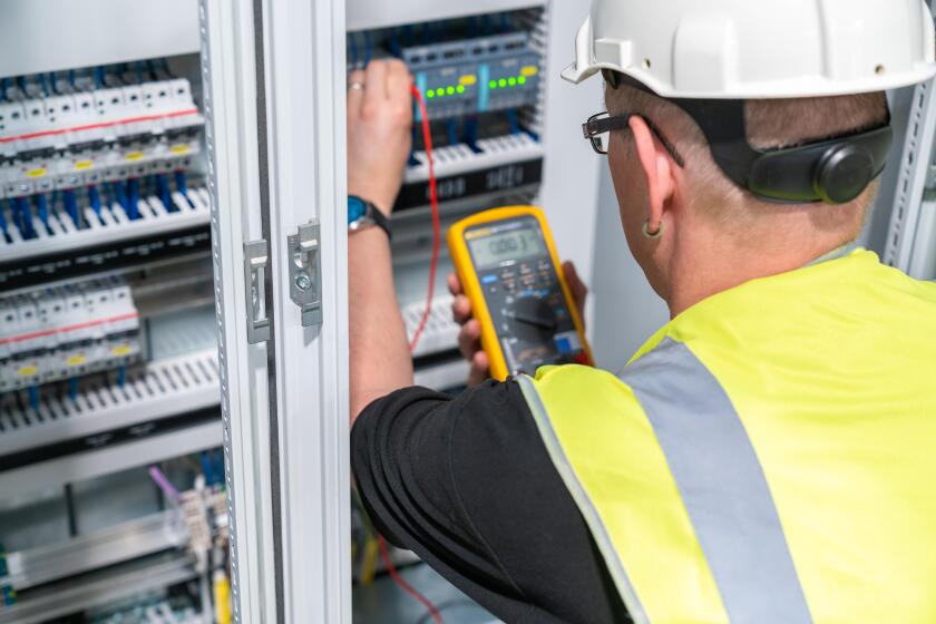 electrical engineer performs a measurement in a control cabinet