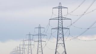 A long straight line of Electricity pylons receding into the distance on Walland Marshes, UK