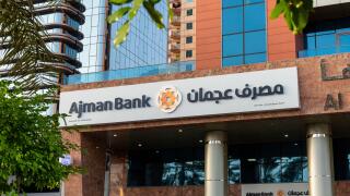 Exterior view of the Ajman Bank branch signage in English and Arabic on a building in Dubai, United Arab Emirates.