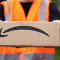 A man delivering an Amazon box with the Amazon smile logo in the UK