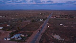 Aerial view of a quiet road passing through a rural landscape at dusk with sparse buildings