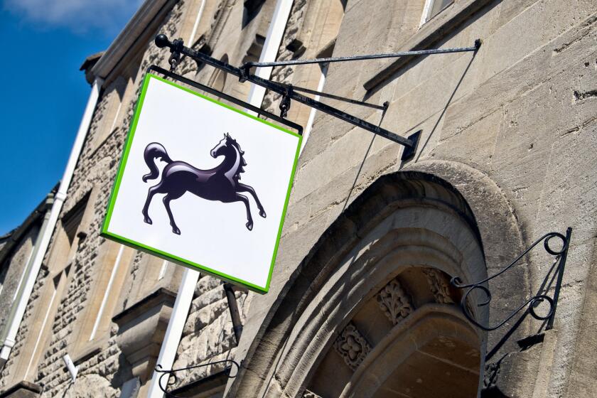 The Lloyds bank black horse sign hanging, displayed over the entrance,outside a UK branch on a sunny day