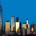 The massive scale of the downtown New York City skyline, with the sun reflecting off the glass and steel architecture.