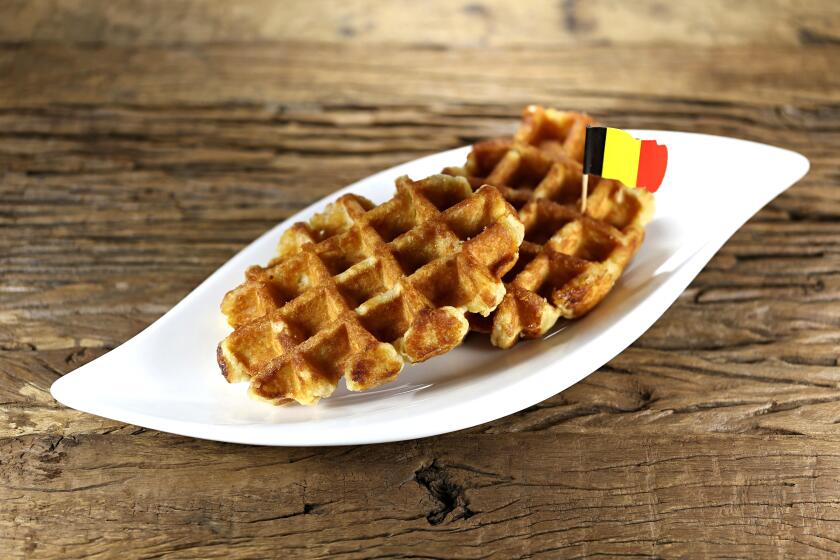 Belgian waffles served on a ceramic plate on rustic wooden background