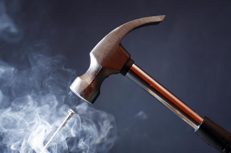 Work tool. Metal hammer above nail with smoke on nice dark background