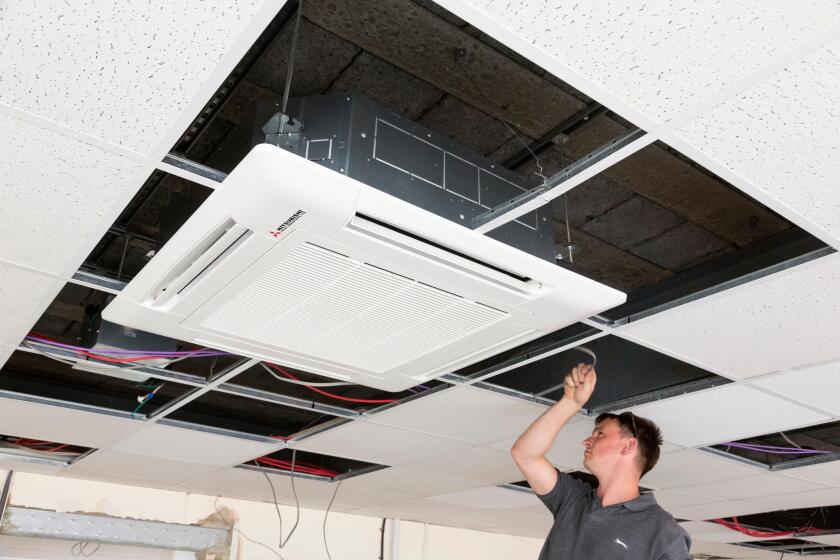 electrician installing air conditioning unit in suspended ceiling