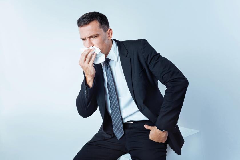 Serious entrepreneur in suit sneezing hard over background