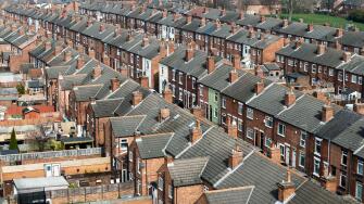 An aerial view above the rooftops of run down back to back terraced houses on a large residential estate in the North of England