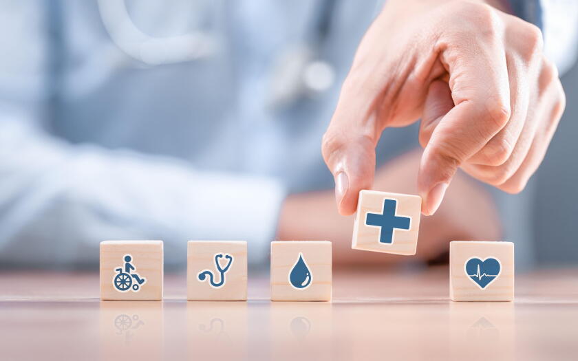 Hand arranging wood block with healthcare medical icon. Health insurance - concept.