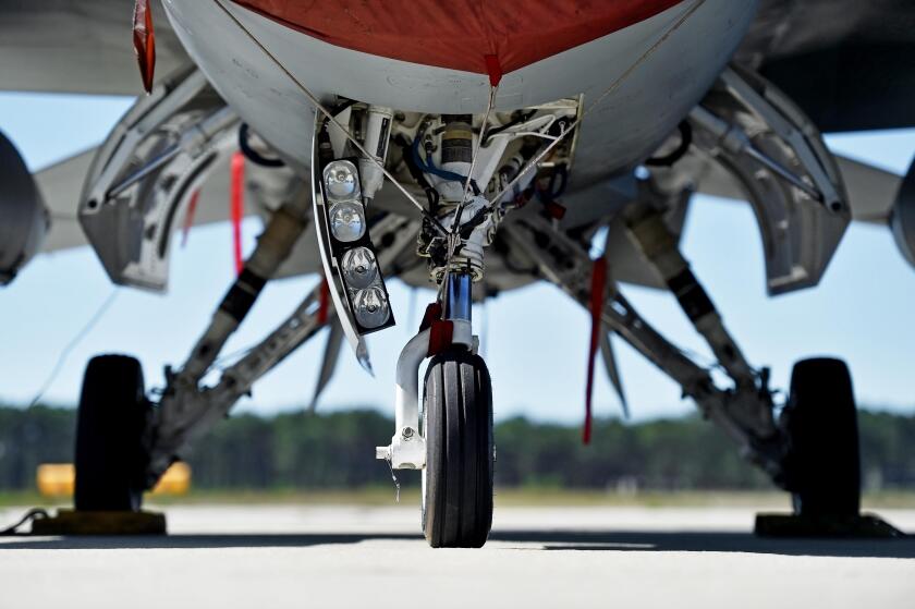 Military aircraft detail with landing gear and engine cover on a runway