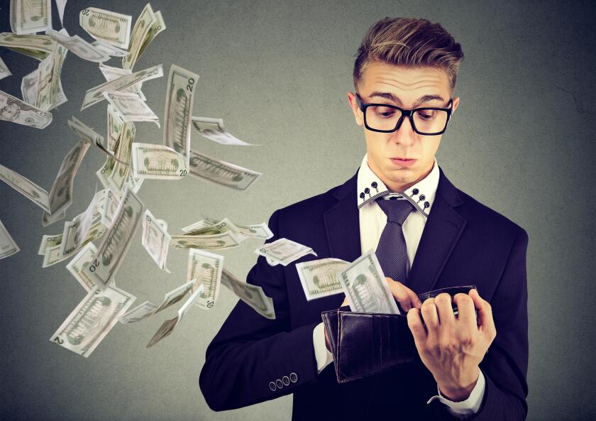 Sad worried business man looking at his wallet with money dollar banknotes flying out away