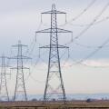 A long straight line of Electricity pylons receding into the distance on Walland Marshes, UK