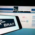Cellphone with logo of investment company Brait SE on screen in front of business website. Focus on center-right of phone display.