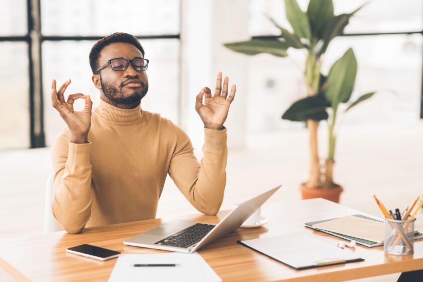 Black man meditating in office coping with stress