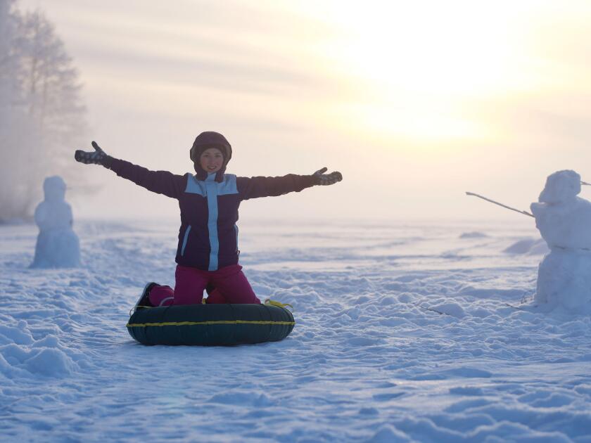 Happy girl enjoying winter activity at frozen lake and winter forest