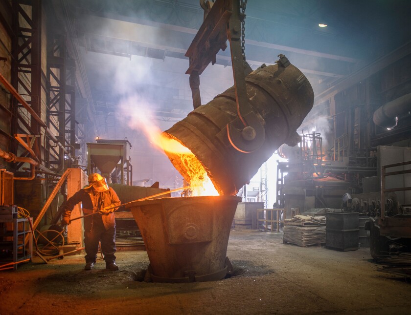 Steel worker and buckets of molten metal in steel foundry
