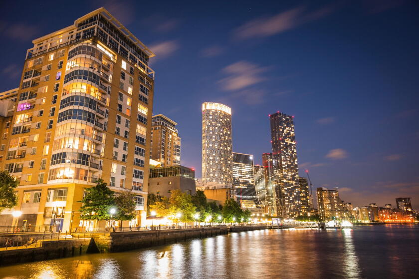 A skyline view of office and condominium towers along The Canary Wharf pier and neighbourhood at dusk.  The Thames River, London UK.