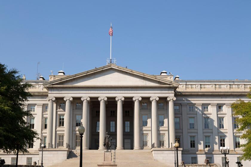The Treasury Building in Washington DC, USA. A statue of Alexander Hamilton stands outside of the Neo-classical Treasury Building.