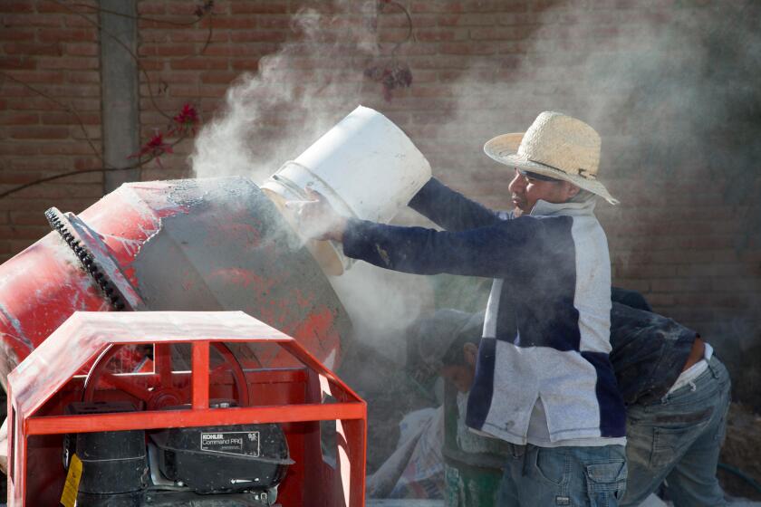San Sebastian Abasolo, Oaxaca, Mexico - Workers mix cement to pave a formerly dirt street in a small rural town of Mexico.
