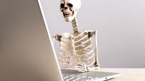 Job burnout. Skeleton sitting at table with laptop. Computer geek. Person suffering from stress at work. Mental and physical exhaustion, fatigue. High quality photo