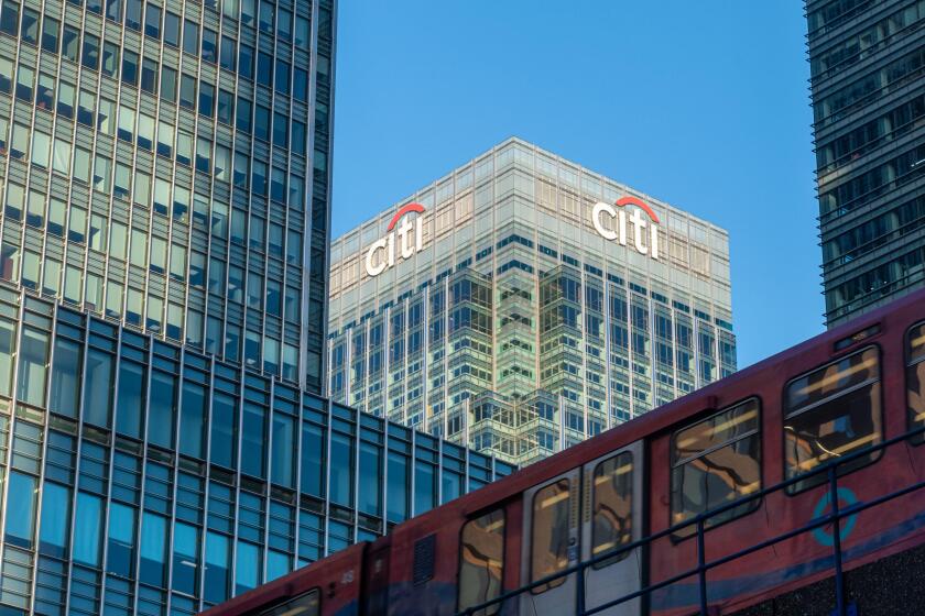 Canary Wharf skyscrapers including Citigroup HQ building (Citi sign and logo) with a DLR Docklands Light Railway train, East London, England, UK