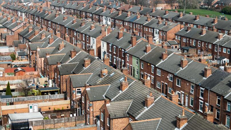 An aerial view above the rooftops of run down back to back terraced houses on a large residential estate in the North of England