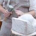 Close up of young sculptor hands working on his marble sculpture in his workshop with hammer and chisel